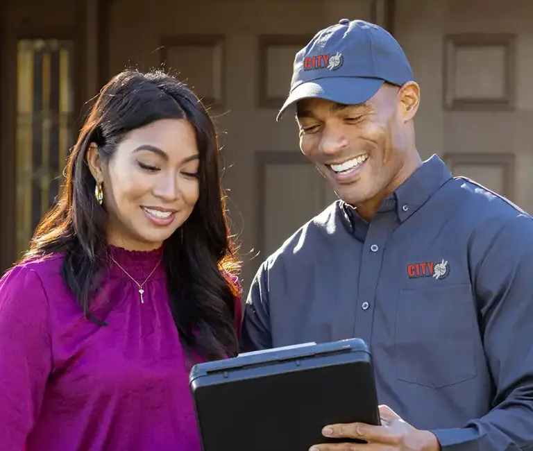 Technician speaking with homeowner in front of a house | City Termite & Pest Control serving Malvern, AR